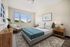 Elegant bedroom with large windows, modern decor, and stylish furniture, offering a serene and inviting atmosphere.