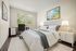 Bright and inviting bedroom with modern decor, featuring a cozy bed, sleek desk by the window, and elegant art pieces.