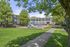 Charming apartment complex with a vibrant playground surrounded by lush greenery and immaculate landscaping under clear blue skies.