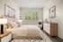 Chic and serene bedroom with cozy bed, modern artwork, and inviting natural light.