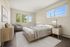 Inviting bedroom with contemporary decor, large windows offering scenic views, and elegant wood furnishings.