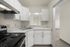 Modern kitchen with sleek white cabinets, elegant marble countertops, and a built-in stove, offering a sophisticated culinary space.