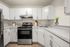 Modern kitchen with elegant white cabinetry, stainless steel appliances, and sleek countertops, accented by a chic plant.