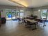 Inviting community room with modern tables and chairs, large windows offering natural light, and a view of the serene courtyard.