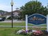 Charming Bay Village apartment community entrance adorned with vibrant flowers and lush greenery, offering a welcoming and picturesque living environment.