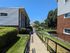 Charming apartment building exterior with well-maintained landscaping and a clear walkway, set against a bright blue sky.