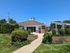 Charming building exterior with a well-maintained lawn, vibrant green shrubs, and clear blue skies highlighting the inviting atmosphere.