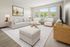 Modern living room with elegant neutral decor, featuring a cozy sofa, glass coffee table, and large windows offering a scenic view.