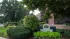 Charming brick apartment building surrounded by lush greenery and vibrant gardens, offering a serene urban living experience.