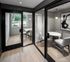 Elegant apartment space featuring two enclosed seating areas with chic glass doors, modern decor, and natural light streaming through a large window with a view of lush greenery.