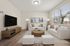 Bright and inviting living room with modern decor, featuring large windows, cozy white sofas, and a stylish wooden coffee table, perfect for relaxation and entertainment.