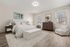 Bright and elegant bedroom featuring a cozy bed with striped linens, modern furnishings, and large windows with natural light.