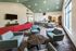 Modern communal living space featuring stylish seating, vibrant red couches, and a well-lit dining area, perfect for social gatherings.
