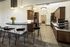 Modern kitchen space with elegant wooden cabinets, sleek countertops, and stylish bar seating. Bright and spacious with contemporary lighting and a touch of nature from a sunflower bouquet.