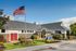 Inviting community center with lush landscaping, striking architecture, and a prominently flying American flag under a clear blue sky.