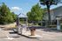 Inviting entrance to a gated apartment community with lush greenery, trees, and a welcoming guard booth.