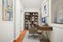 Chic home office with elegant wooden desk, cozy ergonomic chair, and art-filled walls, perfect for productivity.