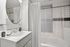 Elegant bathroom with a sleek white vanity, stylish sink, and modern circular mirror, exuding a spa-like ambiance.