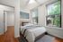 Bright and inviting bedroom with elegant hardwood floors, large windows with a picturesque view, and modern decor.
