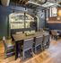 Modern dining area with sleek wooden table, comfortable seating, and stylish kitchenette set against exposed brick walls.