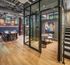 Modern industrial-style room with exposed brick walls, stylish wood flooring, and glass meeting enclosure, ideal for dynamic living and workspaces.