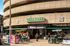 Vibrant urban scene outside a popular retail store with people enjoying outdoor seating and lush greenery.