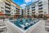 Luxurious apartment courtyard featuring a sparkling pool with sun loungers, surrounded by modern multi-story buildings with balconies.