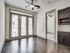Bright apartment interior with floor-to-ceiling windows, elegant hardwood flooring, and modern ceiling fan, offering a sophisticated living space.