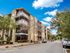 Modern apartment complex with contemporary design, lush landscaping, and multiple balconies under a bright blue sky.