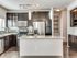 Modern kitchen with sleek dark wood cabinets, granite countertops, and stainless steel appliances, accented by stylish pendant lighting.