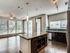 Bright and modern open-concept kitchen and living area with large windows, elegant wooden flooring, and sleek pendant lighting.