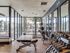 Modern fitness center with floor-to-ceiling windows, featuring a variety of weightlifting equipment and serene views.
