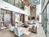 Luxurious modern living room with high ceilings, elegant sofas, and stylish lighting in a sunlit space.