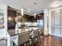 Modern kitchen with elegant dark cabinets, sleek countertops, and stylish bar stools in a cozy apartment.