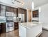 Modern kitchen featuring sleek stainless steel appliances, elegant dark wood cabinets, and a spacious granite countertop island with pendant lighting.
