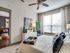 Inviting bedroom with modern decor, featuring a large window, cozy bedding, and elegant accents. Adjacent room offers additional seating with colorful cushions.