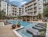 Luxurious apartment complex featuring an inviting pool area with elegant lounge chairs, surrounded by modern multi-story buildings.