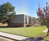 Charming apartment complex with attractive brick exterior, lush green lawn, and pathways lined with vibrant trees.