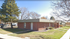 Charming brick building surrounded by lush greenery and mature trees, offering a serene and welcoming environment.