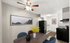 Modern apartment dining area with elegant wooden table, stylish black and blue chairs, and a vibrant yellow floral centerpiece, adjacent to a sleek kitchen with black appliances.