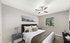 Elegant bedroom with plush bedding, stylish decor, large window with natural light, and modern ceiling fan.