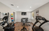 Modern apartment gym with state-of-the-art exercise equipment, weights, and a wall-mounted TV for an invigorating workout experience.