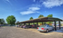 Spacious covered parking area under a clear blue sky, highlighting ample parking space amidst lush greenery.