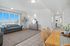 Bright and inviting living space featuring a cozy grey sofa, large windows with a scenic view, elegant d&eacute;cor, and a wooden dining set, perfect for modern living.