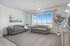 Bright, inviting living room with large windows, stylish grey sofas, and elegant decor, offering a serene view.