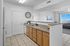 Bright and modern kitchen featuring elegant granite countertops, ample wooden cabinetry, and an inviting peek into a sunlit living room with expansive windows.