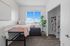 Bright and airy bedroom featuring a cozy bed, stylish decor, and a large window with scenic views. Spacious open closet adds convenience.