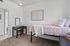 Charming bedroom with soft pink bedding, elegant wall art, and a cozy workspace, perfect for a serene retreat.