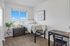 Bright bedroom with a cozy bed, large window offering city views, sleek desk for productivity, and stylish decor.