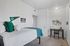 Bright and inviting bedroom with a comfortable twin bed, study desk, and vibrant green accents, perfect for a student living space.